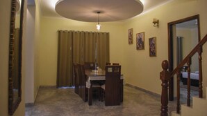 A dining area with a table and chairs, a ceiling light, and a staircase. - Pinewood Manor Kasauli (Solan)