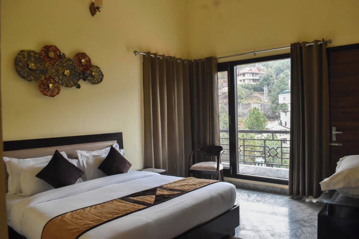 A hotel room with a bed, a chair, and a balcony with curtains.