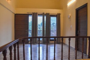 A hotel room with a wooden staircase, a large sliding glass door, and a view of greenery outside.