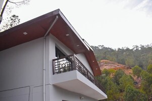 A modern building with a white facade and a balcony with a metal railing.