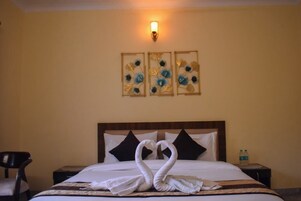 A hotel room with a bed, a nightstand, a chair, and wall art.