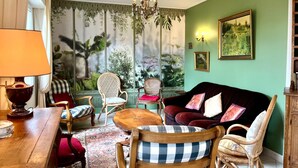 Een kamer met een groot raam, een kroonluchter, een groene wand en een schilderij.