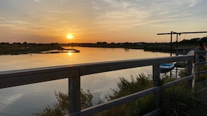 Een zonsondergang boven een rustig meer met een houten steiger en een klein bootje.