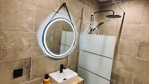 A bathroom with a round mirror, a sink, a shower, and a toilet. - Le Bois Gentil 3* - lounge + sleeping area, pets welcome (La Clusaz)