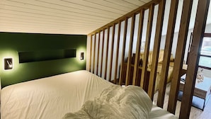 A bedroom with a bed, wooden slats, and a green wall. - Le Bois Gentil 3* - lounge + sleeping area, pets welcome (La Clusaz)