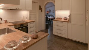 A modern kitchen with white cabinets, a wooden countertop, and a dining area visible through an archway. - Beautiful home in Glesborg with WiFi (Glesborg)