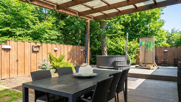 An outdoor patio with a wooden deck, a table with chairs, and a hot tub. - Beautiful home in Glesborg with WiFi (Glesborg)