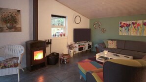 A cozy living room with a fireplace, a sofa, a colorful ottoman, and a television. - Beautiful home in Glesborg with WiFi (Glesborg)