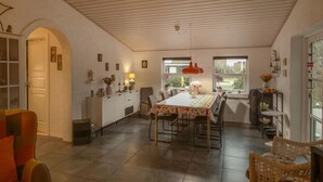 A dining area with a long table, chairs, and a kitchen area with a white cabinet and counter. - Beautiful home in Glesborg with WiFi (Glesborg)