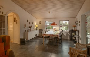 A dining area with a long table, chairs, and a kitchen area with a white cabinet and counter. - Beautiful home in Glesborg with WiFi (Glesborg)
