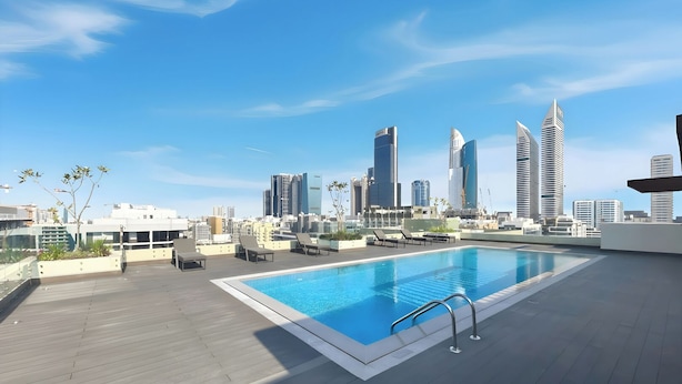 Ein Pool auf dem Dach mit Liegestühlen und einer Stadtansicht im Hintergrund.