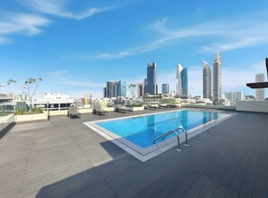 A rooftop pool with lounge chairs and a city skyline in the background. - 1BR Stay Near World Trade Center Metro (Dubai)