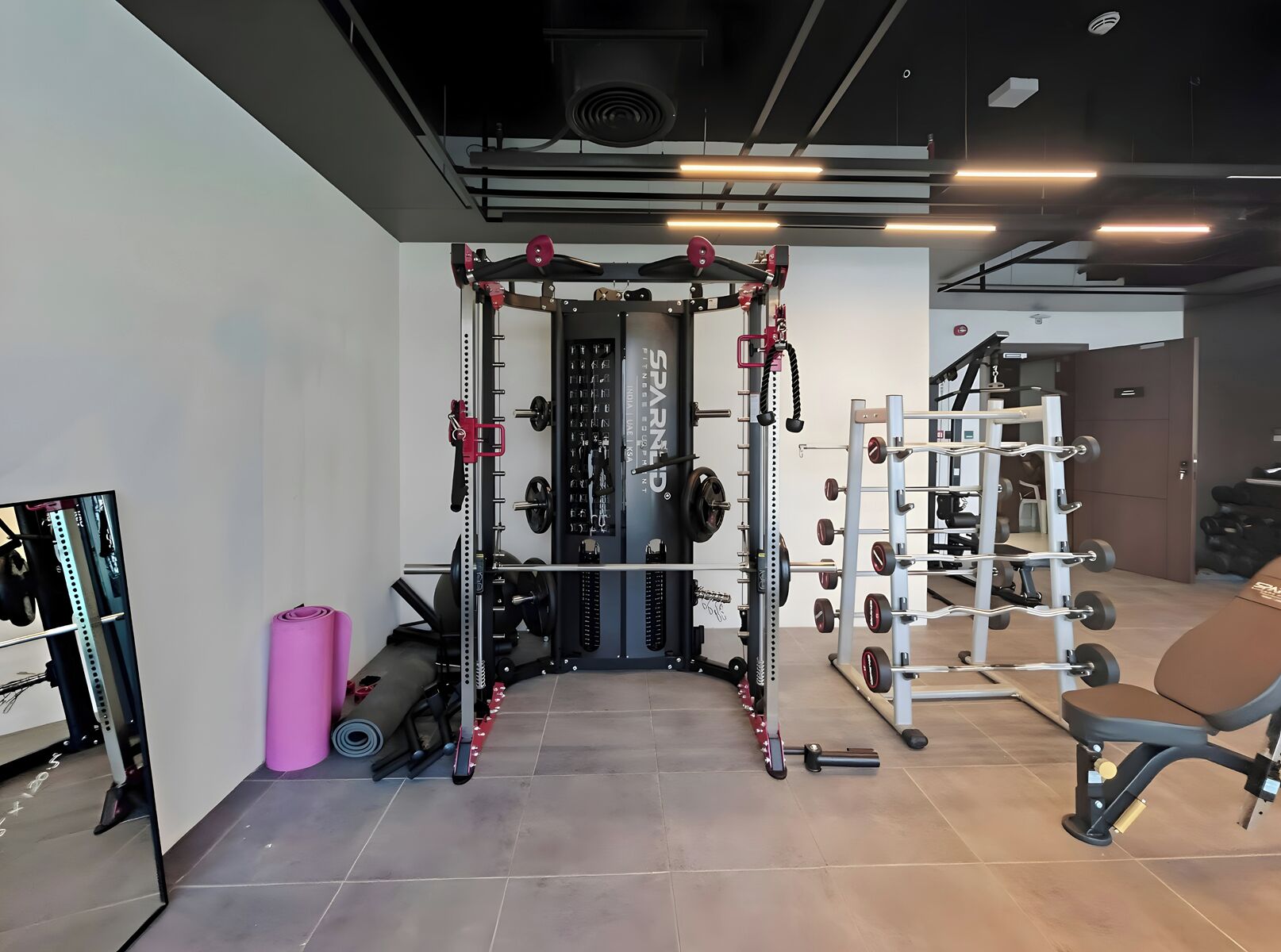 A gym with a squat rack, bench press, and various weight plates.