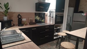 A modern kitchen with black cabinets, a wooden countertop, a sink, a coffee maker, and a clock. - Gîte 4 people, air-conditioned, swimming pool, 30mn Puy du Fou, with family or friends. (Chantonnay)
