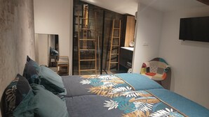 A bedroom with a bed, a chair, a ladder, and a TV mounted on the wall. - Gîte 4 people, air-conditioned, swimming pool, 30mn Puy du Fou, with family or friends. (Chantonnay)
