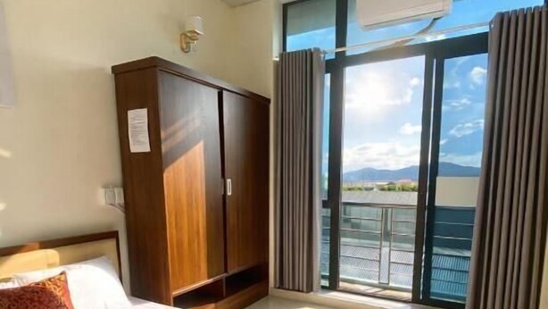 Habitación de hotel con cama, armario, ventana con cortinas y equipo de aire acondicionado.
