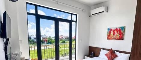 Un dormitorio con cama, televisión, ventilador y balcón con vistas.