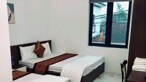 Una habitación con dos camas, una ventana con vistas al exterior y un equipo de aire acondicionado.