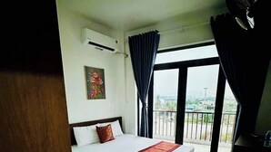 Habitación de hotel con una cama, una mesita, una ventana con cortinas y vistas al exterior.