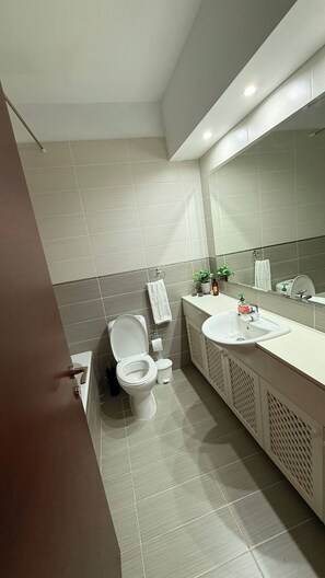 Ein modernes Badezimmer mit Toilette, Waschbecken und Spiegel.
