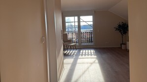 Una habitación amplia con un gran ventanal, una silla y una planta en maceta.