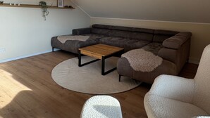 Una sala moderna con un sofá modular, una mesa de centro y dos sillones.
