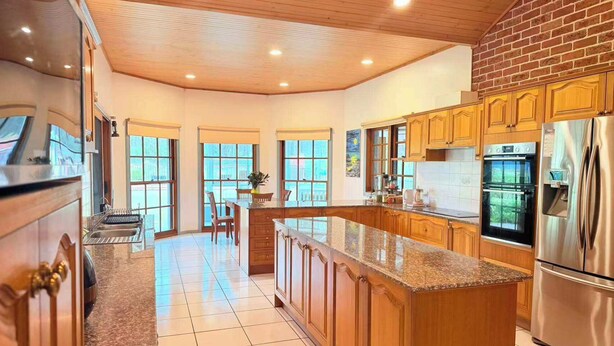 Una cocina amplia con armarios de madera, encimera de granito y electrodomésticos de acero inoxidable.