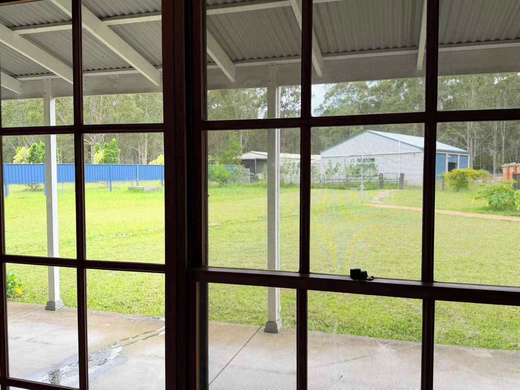 Uma área de varanda coberta com vista para um gramado e uma cerca azul.
