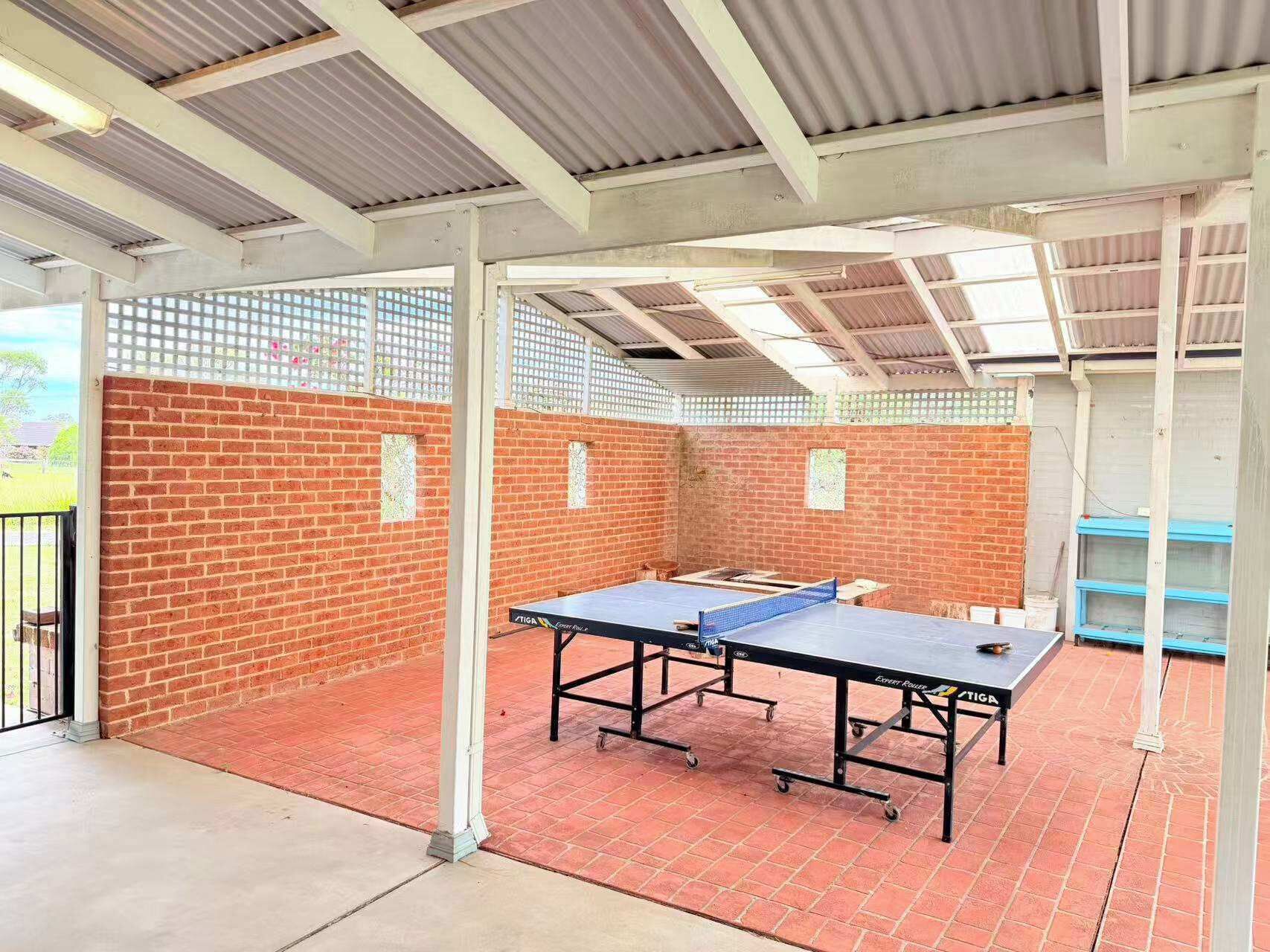 An indoor ping pong table area with a brick wall and metal beams.