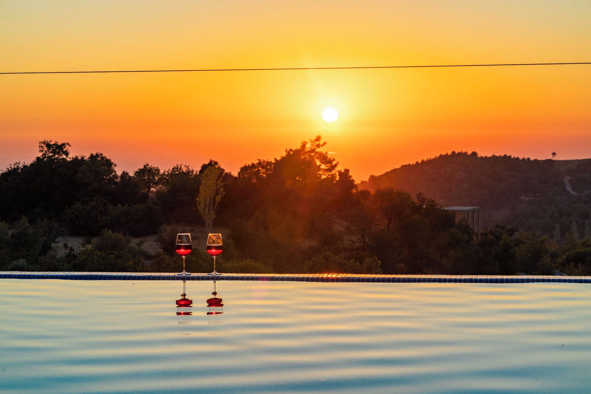 A sunset over a calm body of water with two red traffic signs in the foreground.