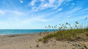 A beach with sand, grass, and the ocean under a clear sky. - CT 7616 Golf Course View - Welcome! (Fort Pierce)