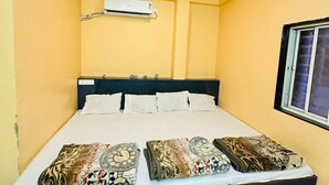 Quarto com cama, ar condicionado, ventoinha no teto e janela.