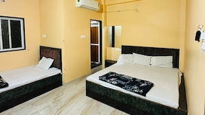 Quarto de hotel com duas camas, ventilador de teto, ar condicionado e janela.