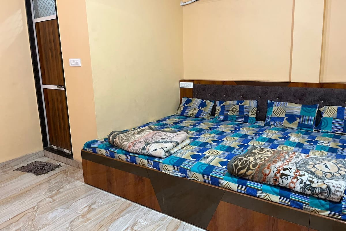 A bedroom with a bed, a wooden door, and an air conditioning unit.