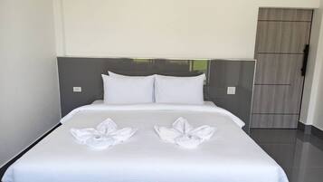 Una cama bien hecha con sábanas blancas y dos toallas dispuestas en un diseño floral sobre la colcha.