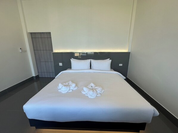 A hotel room with a large bed, two pillows, and a headboard with built-in lighting.