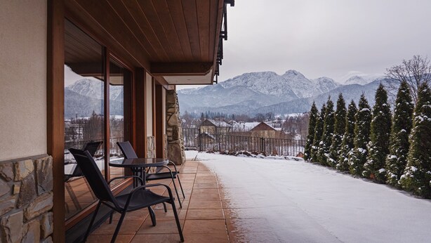 Ein überdachter Außenbereich mit Steinmauern und Blick auf schneebedeckte Berge.