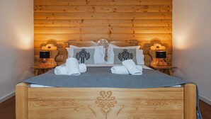 Ein Schlafzimmer mit Holzwandverkleidung, einem Bett, zwei Nachttischlampen und dekorativen Kissen.