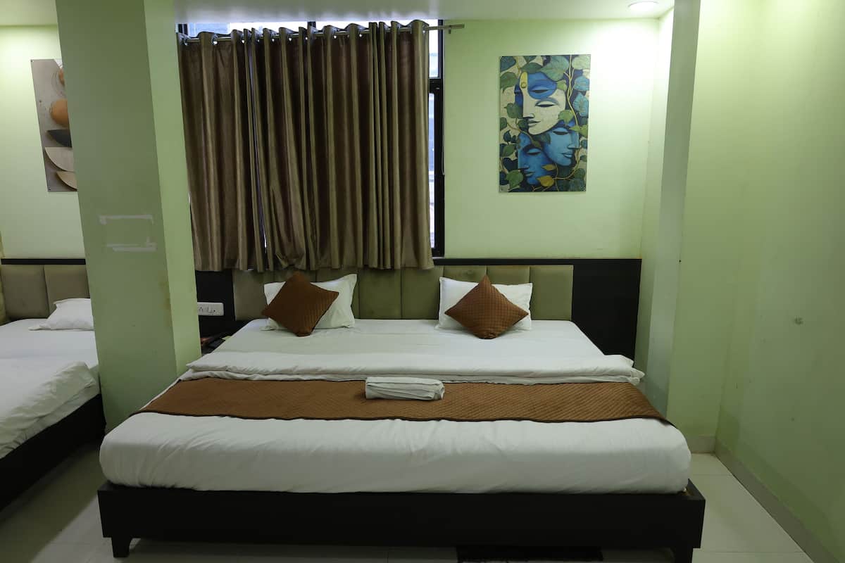 A hotel room with a large bed, two pillows, a brown throw blanket, and a painting on the wall.