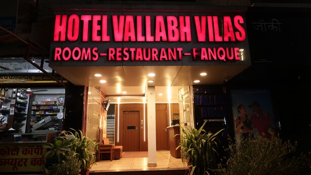 Een hotelentree met een neonbord waarop staat dat er kamers, een restaurant en een speelhal zijn.