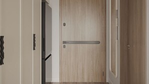 A hallway with a wooden door, a door handle, and a light switch on the wall. - The Aura Patong (Patong)