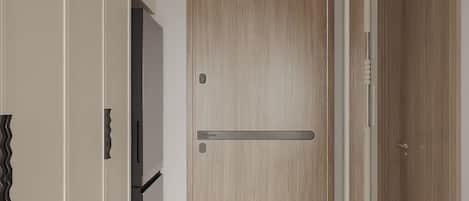 Un pasillo con una puerta de madera, un picaporte y un interruptor de luz en la pared.
