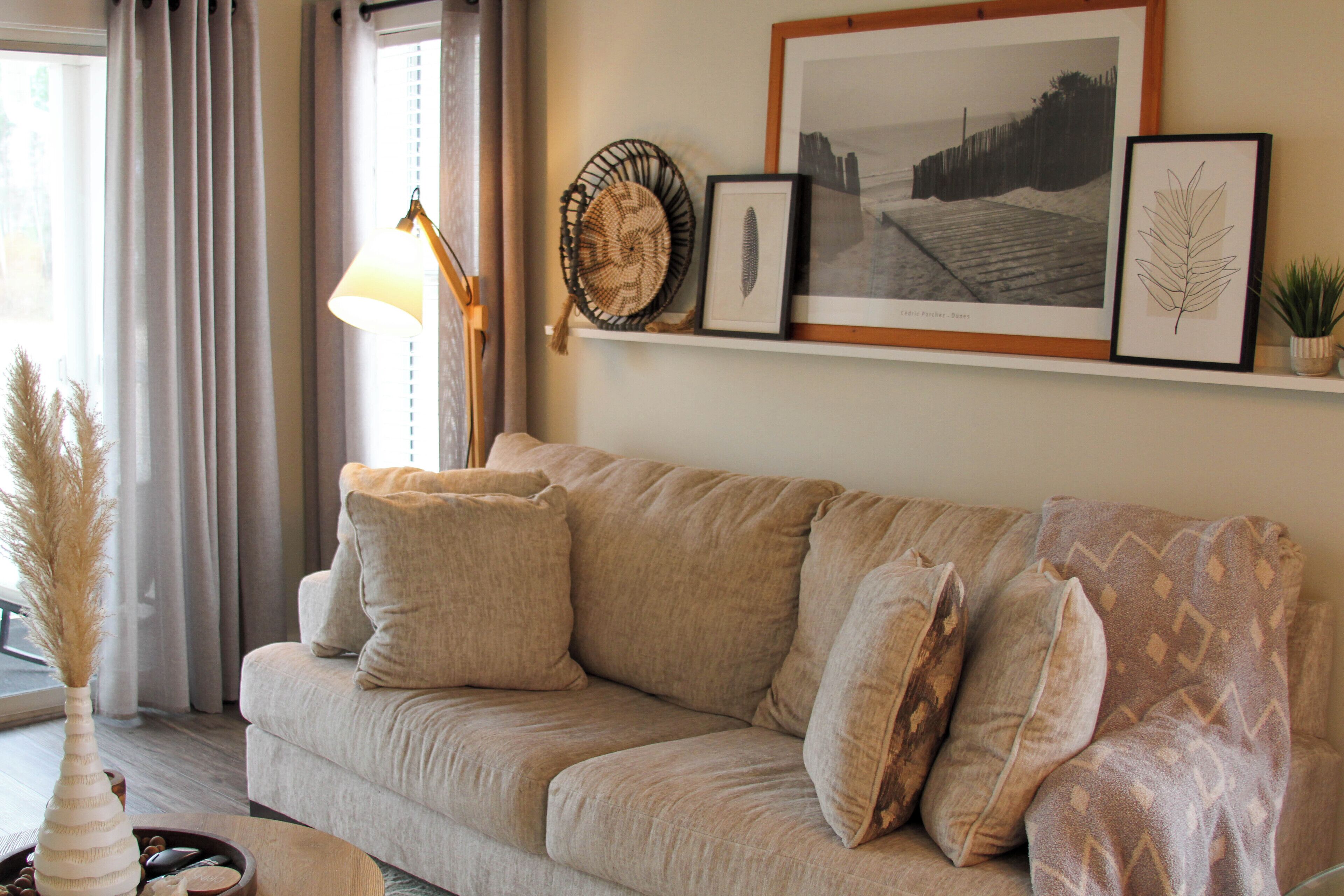 A living room with a beige sofa, a lamp, and framed artwork on the wall.