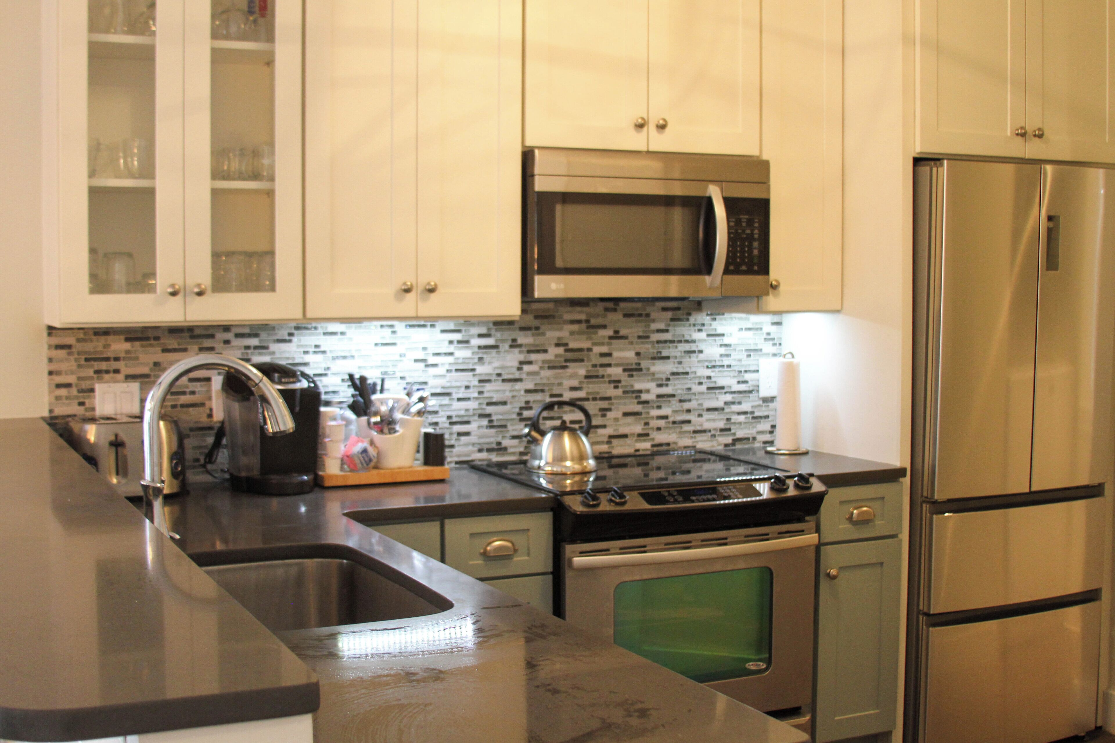 A modern kitchen with stainless steel appliances, a microwave, a kettle, and a built-in oven.