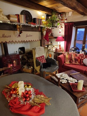 A cozy living room with a fireplace, a dining table with a festive centerpiece, and a comfortable sofa. - Guest Room 'La Maison de Justine' with Shared Pool, Private Terrace and Wi-Fi (Le Fel)