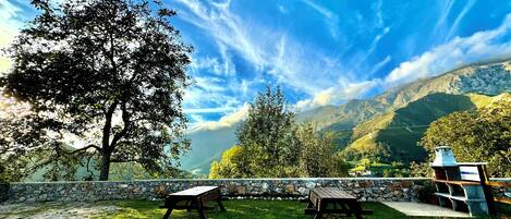 A picnic area with stone walls and wooden benches, overlooking a mountainous landscape.
