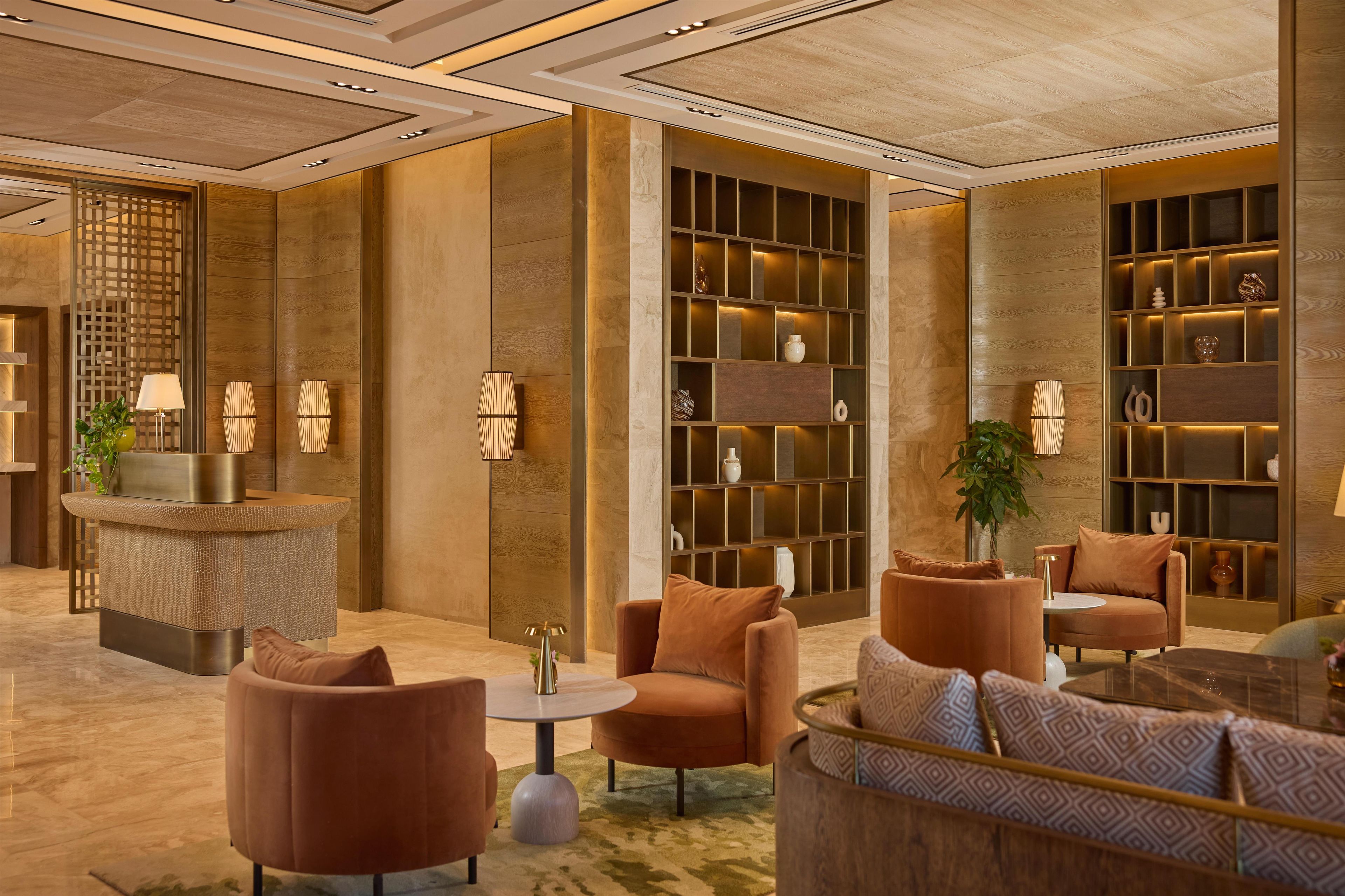 A modern lobby with a reception desk, seating area, and decorative shelves.