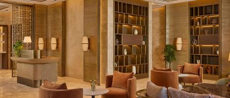 A modern lobby with a reception desk, seating area, and decorative shelves.