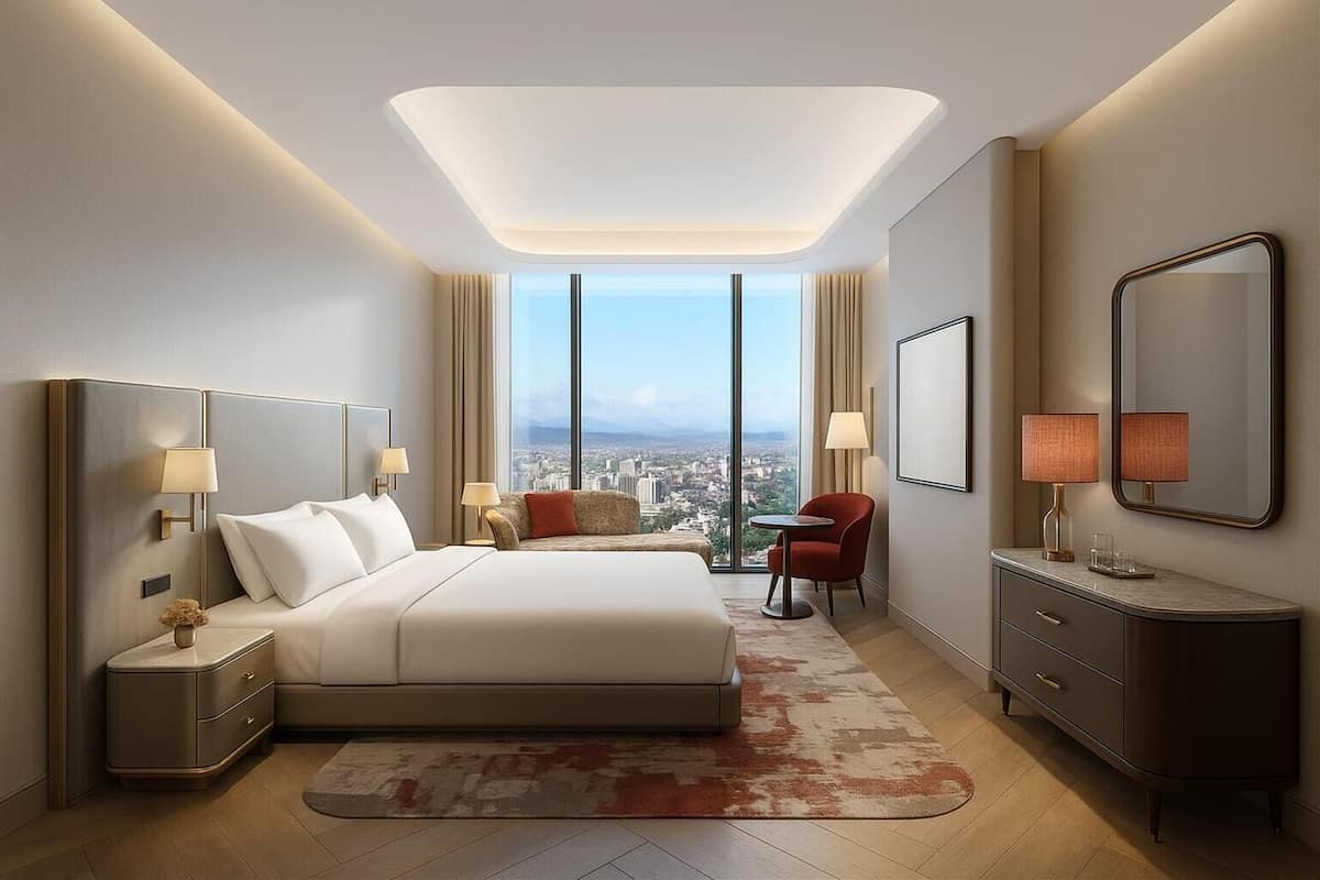 A modern hotel room with a large bed, a desk, a chair, a nightstand, a mirror, and a view of the city.