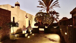 A courtyard with a cobblestone path, palm trees, and a building with a dome and a flag. - Villas Mamma Mia  A pool heat Private (Castillo del Aguila)